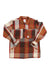 The Topo Designs Womens Mountain Shirt Jacket is a long-sleeve, oversized workwear layer with a large orange, brown, cream, and red plaid pattern. It features a collar, two chest pockets, and black buttons for classic mountain-inspired style.
