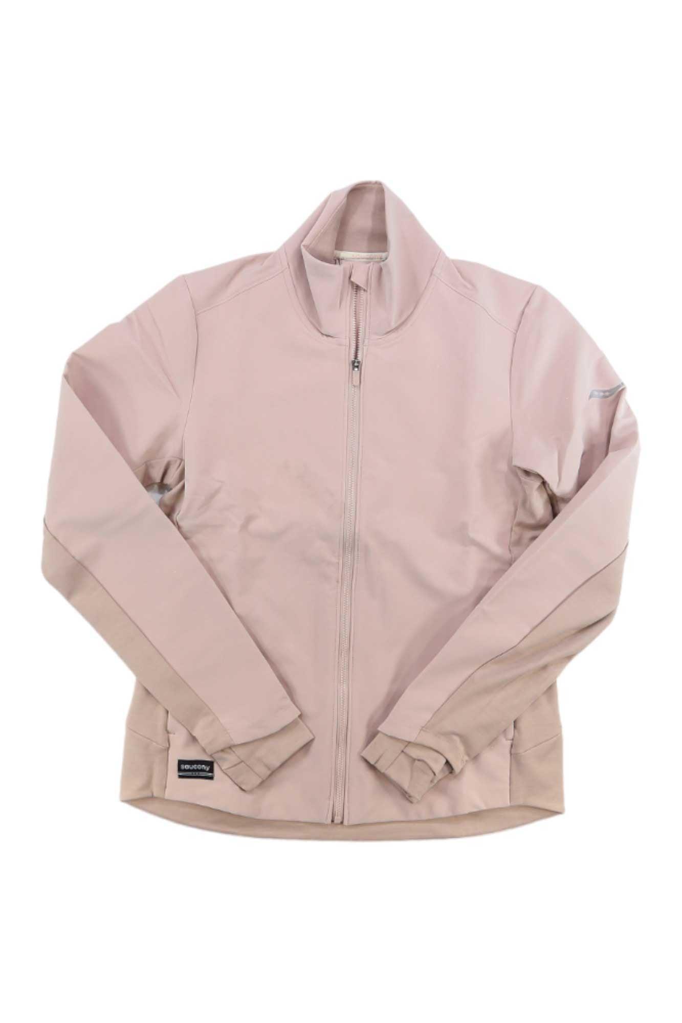 The Saucony Women's Triumph Jacket is a light pink running jacket with a high collar and long sleeves, made from smooth, lightweight, wind- and water-resistant material. The jacket is shown laid flat on a white background.