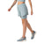 A person is walking in a light blue sports bra, Smartwool Womens Intraknit Active Lined Short, and blue athletic shoes. The photo is cropped above the shoulders, showing a tattoo on one arm.