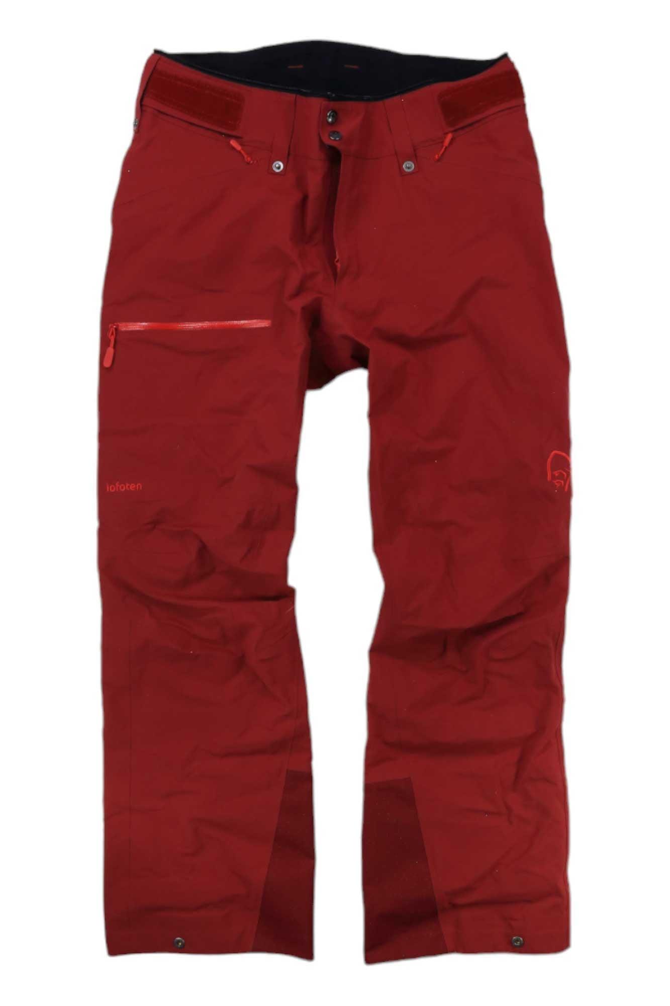 The Norrona Womens Lofoten GORE-TEX Pants are red freeride ski pants with a front button and zip closure, zippered side pocket, and reinforced knees and ankles—laid flat on white, these waterproof pants are perfect for outdoor adventures.
