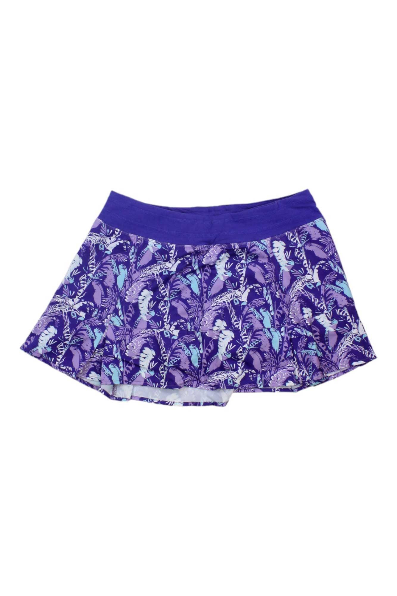 The Tasc Women's Rhythm 13 Inch Skirt is a purple flared athletic skirt with a comfy waistband, floral and leaf print in light blue, lavender, and white, plus built-in compression shorts for extra support.