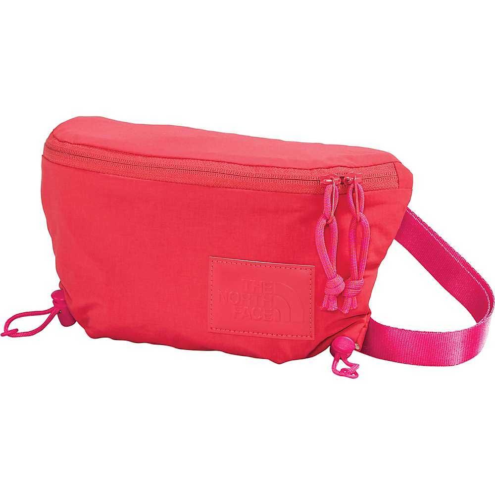 The North Face Women's Never Stop Lumbar Waist Pack in bright pink is made from recycled nylon and features a zippered main compartment, adjustable strap, subtle logo patch, and pink zipper pulls with cord accents.