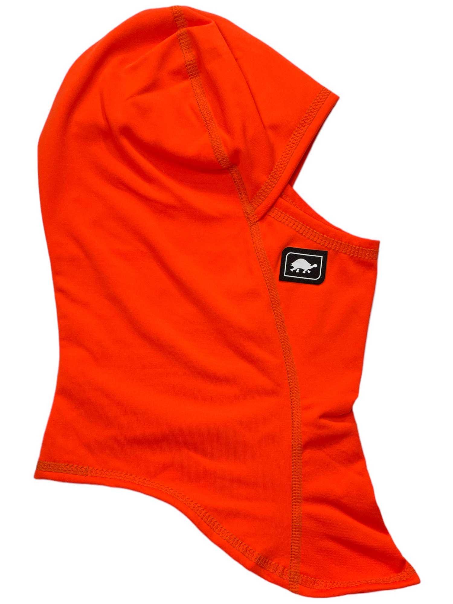 The Turtle Fur Comfort Shell Ninja Balaclava is a bright orange, lightweight hooded mask with a face opening and features a small black patch with a white animal logo on the side for style and comfort.