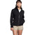 A woman in The North Face Women's Apex Flex FUTURELIGHT Jacket stands in beige shorts with one hand in her pocket, gazing ahead with a faint smile against a plain white background.