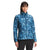 A woman stands facing forward, modeling The North Face Women's Printed ThermoBall Eco Jacket—a blue patterned, quilted jacket with a high collar—paired with black pants against a plain white background.