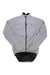 The Sugoi Men's Zap Bike Jacket is light gray with a subtle checkered pattern, windproof and waterproof fabric, front zipper, high collar, small chest logo, and an extended mesh hem at the back. Shown laid flat on a white background.