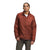 A person with braided hair models the rust-colored The North Face Mens Circaloft Jacket over a white t-shirt and green pants, set against a plain white background.