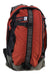 The Osprey Heritage Simplex Backpack, featuring a red and black design, gray straps, a front logo patch, and made from recycled nylon, is standing upright against a white background.