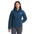 A woman models The North Face Womens Belleview Stretch Down Hoodie in blue with a hood, paired with gray pants. She stands facing forward, smiling with one hand in her pocket against a plain white background.