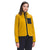 A woman stands facing forward against a plain white background, wearing the yellow The North Face Women's Mountain Sweatshirt Hoodie with a black front zipper and chest pocket, Ventrix insulation, and black pants.