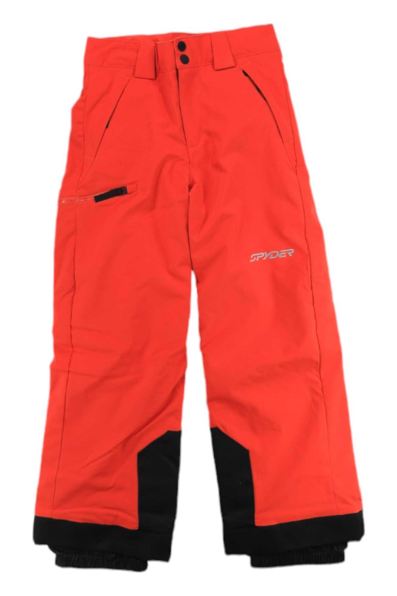 The Spyder Boys Propulsion Pant features bright orange color, black reinforced cuffs, front and zippered side pockets, and the white Spyder logo on the upper leg. These waterproof ski pants are ideal for winter adventures.