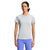 A woman in a light gray The North Face Womens Elevation SS Top made with recycled polyester and bright blue leggings stands against a white background, looking slightly to her right with a neutral expression.