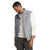 A man wearing The North Face Men's Big ThermoBall Eco 2.0 Vest in light gray over a white long-sleeve shirt and gray pants stands, smiling as he looks down with his left hand in his pocket.