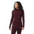 A woman with curly hair smiles and looks left, wearing a burgundy Smartwool Womens Thermal Merino Drape Neck Hoodie with front pockets and matching leggings against a plain white background.