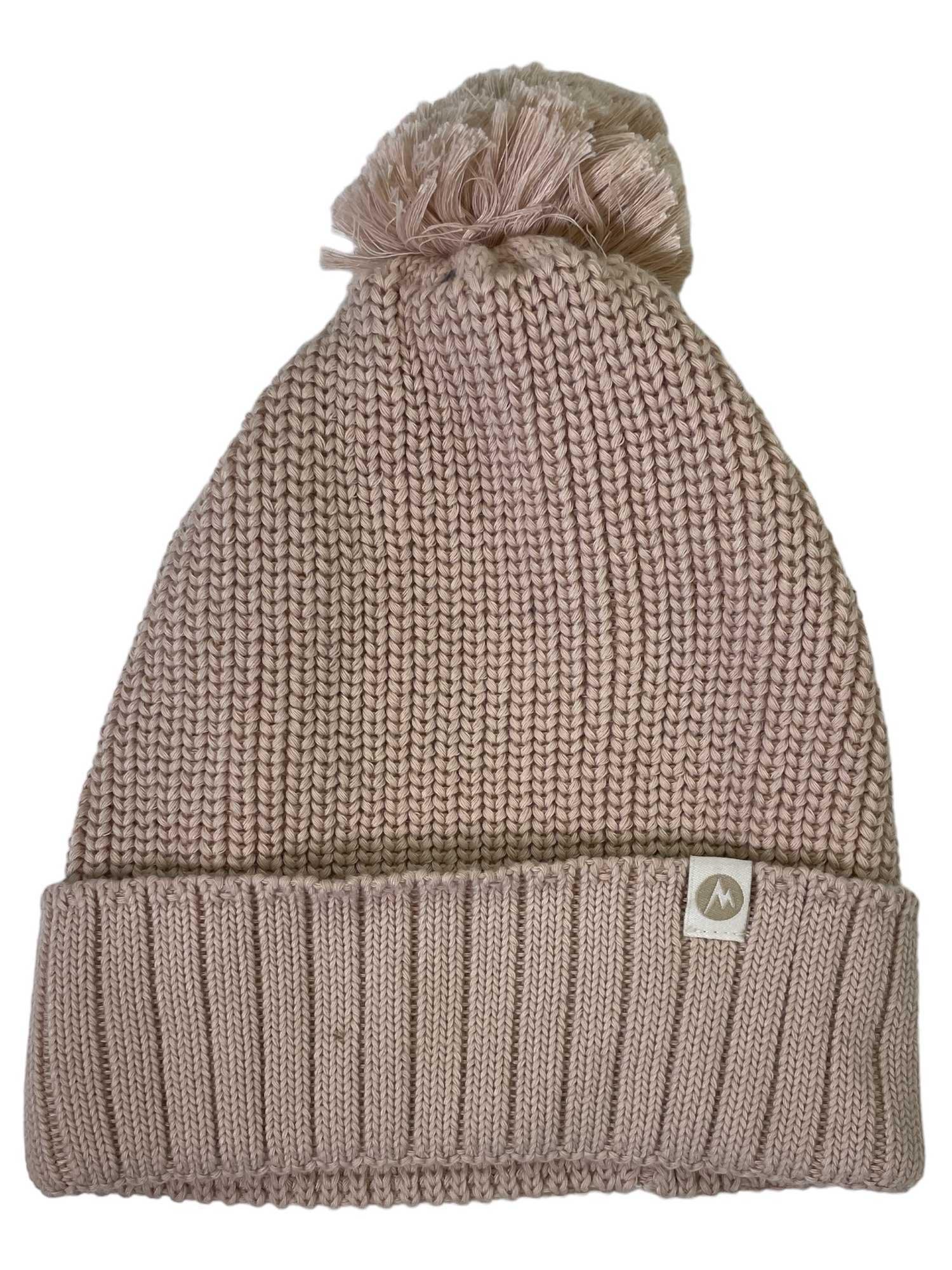 The Womens Snoasis Pom-Pom Beanie is a light pink winter hat with a cozy pom-pom, folded brim, and a small rectangular tag featuring a mountain logo—combining warmth, style, and functionality.