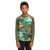 A boy in black pants and The North Face Boys' Sun LS Tee with olive green sleeves and a colorful camo pattern stands facing forward against a white background; the UPF 50 fabric provides added sun protection.