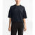 A person stands facing forward against a plain white background, wearing The North Face Women's Sleek SS Knit Top with short sleeves and a relaxed fit, paired with black pants featuring The North Face logo on the left thigh.