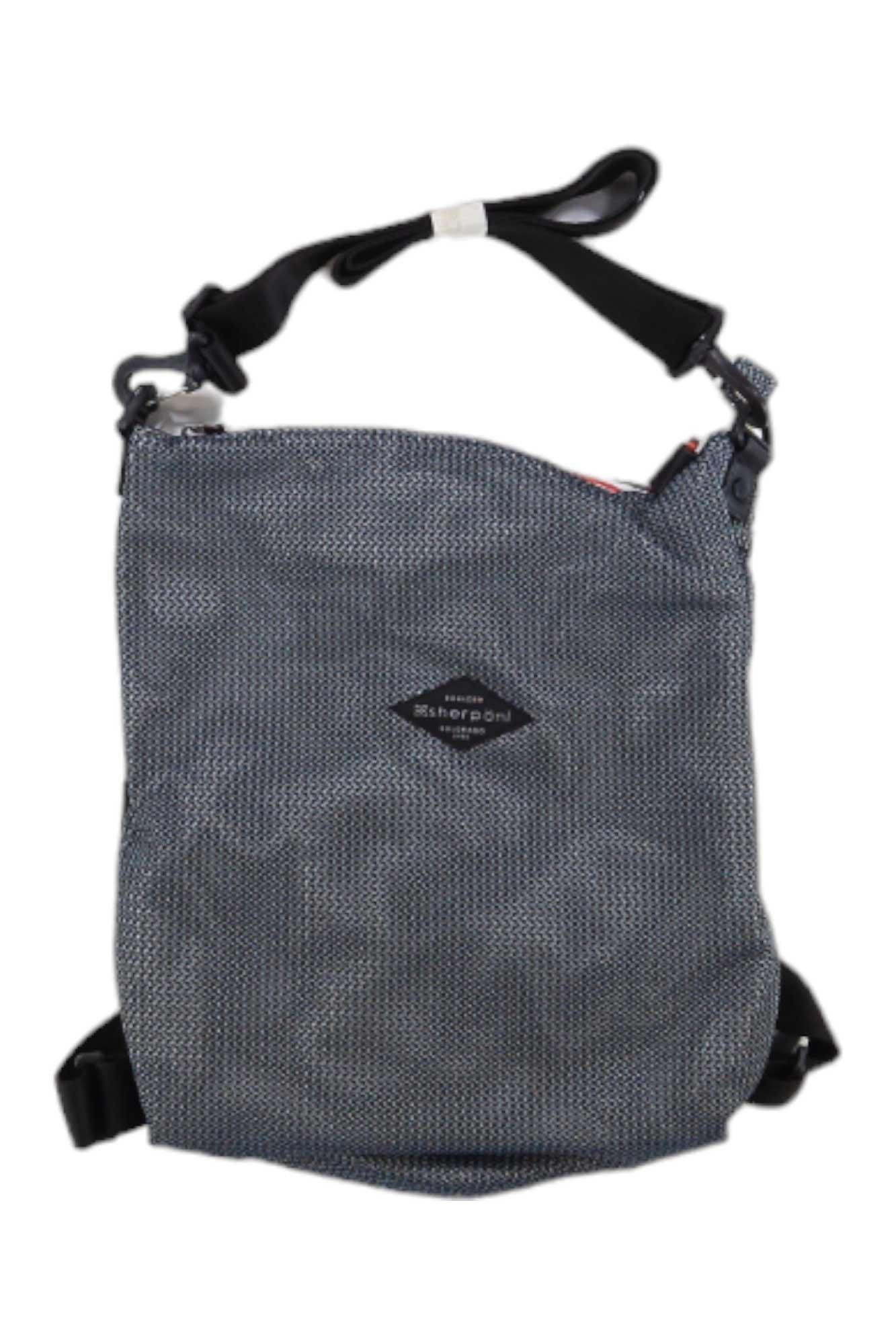 The Sherpani Delanie Crossbody Bag + Backpack is a gray, textured, water-resistant bag with a black adjustable strap and a small diamond-shaped logo patch on the front, displayed against a white background.