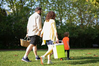 man and woman carrying a cooler walking at the park with child