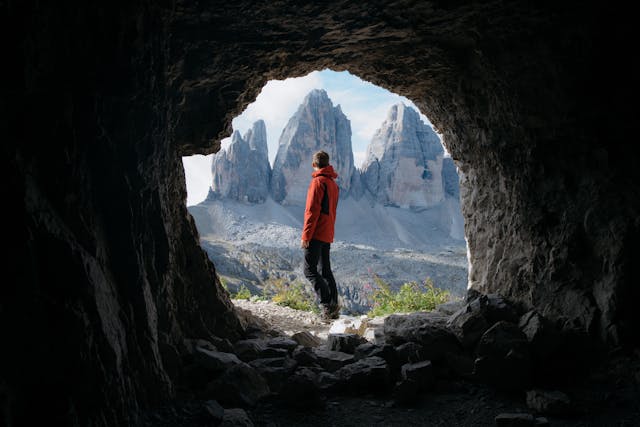 man standing outside of a mountain cave