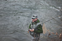 man wearing fishing apparel by river