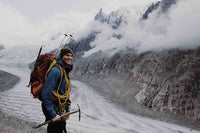 A man with rock climbing gear next to a mountain