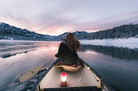 a woman paddling a canoe toward a mountain