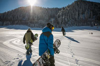 people carrying snowboards under a sunny sky