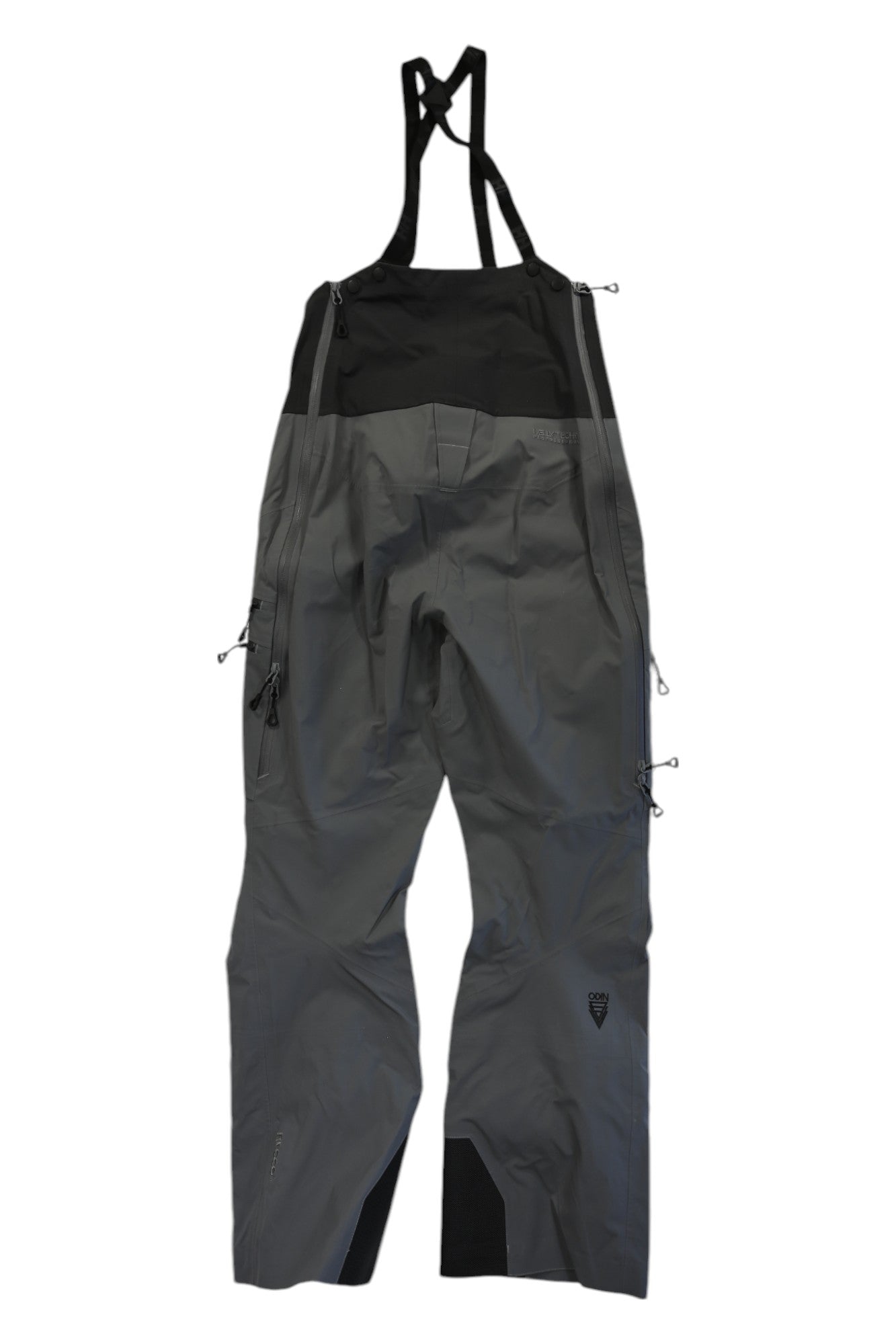 The Helly Hansen Womens Odin Mountain 3L Shell Bib Pants in gray and black feature suspenders, zipper closures, and reinforced knees and ankles. These mountain adventure pants are displayed flat on a white background.