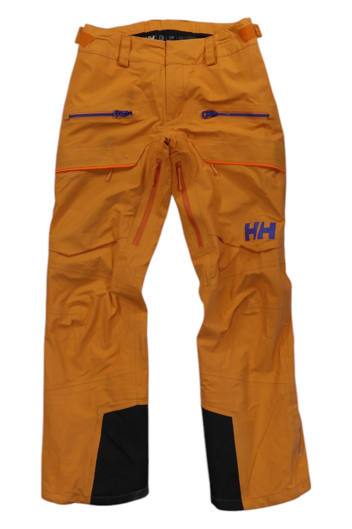 The Helly Hansen Womens Aurora Shell Pant comes in bright orange with purple zippers, reinforced black inner cuffs, HH logo on the left thigh, multiple pockets, and belt loops for a secure winter ski fit.