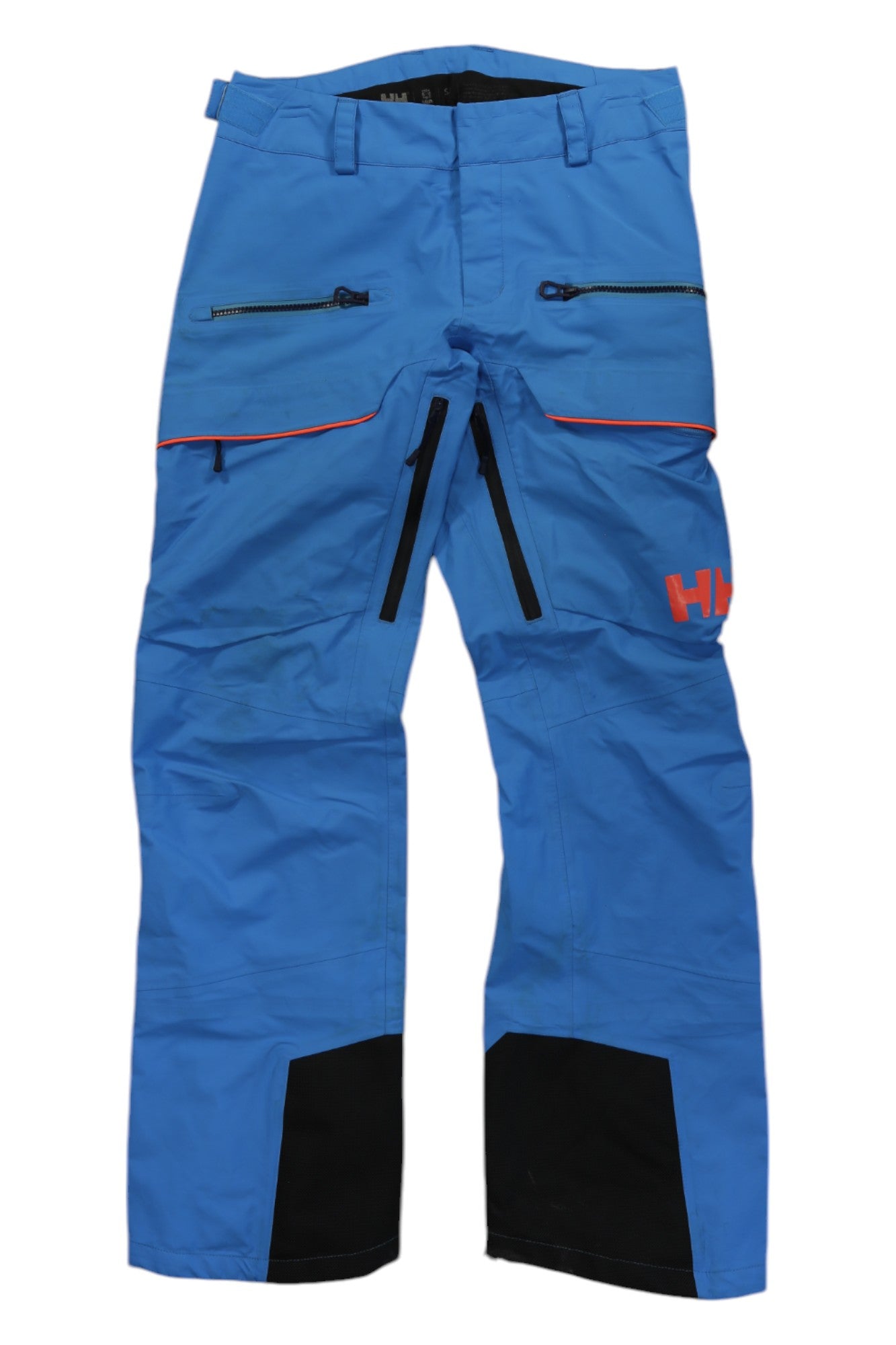 The Helly Hansen Womens Aurora Shell Pant features a bright blue shell, black reinforced cuffs, zippered thigh pockets with bold black zips, and a red HH logo on the left thigh. Ideal for skiing, hiking, and all winter adventures.