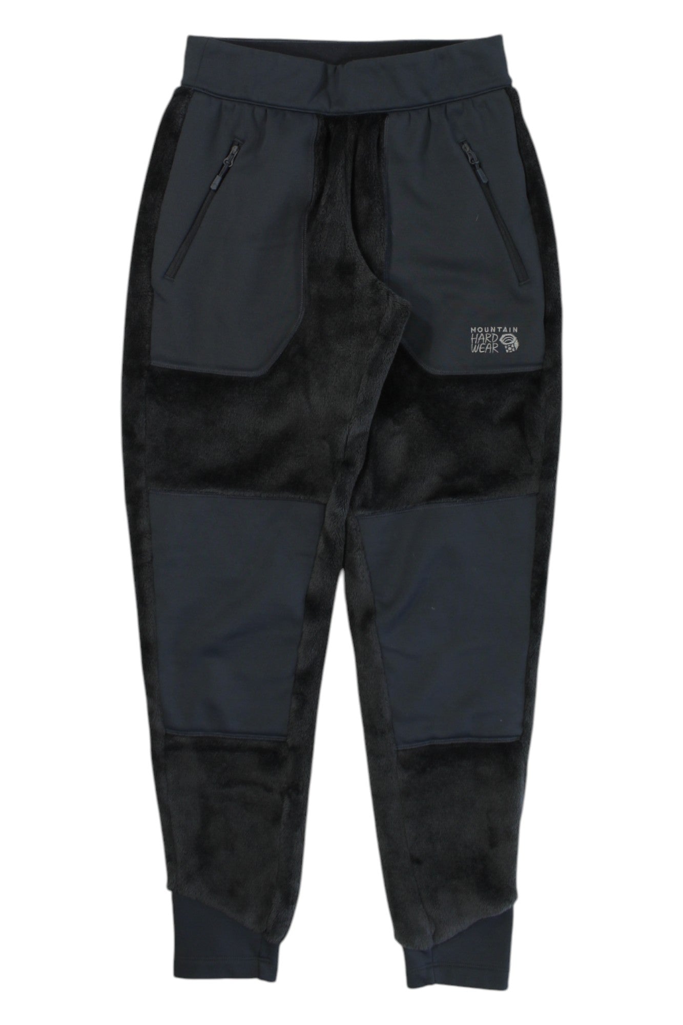 The Mountain Hardwear Womens Polartec High Loft Pant features black and dark gray fleece, zippered pockets, elastic waistband, cuffed ankles, cold-weather insulation, patchwork details, and a logo on the left thigh.