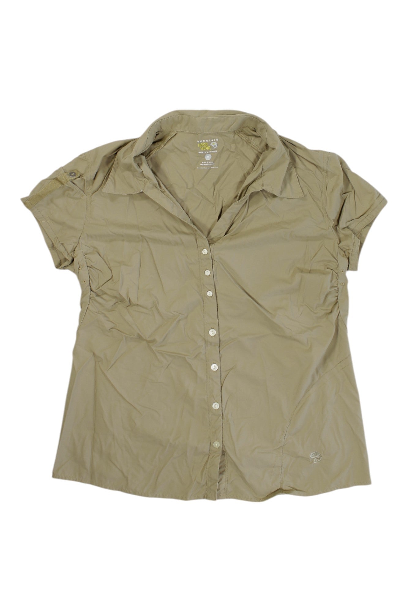 The Mountain Hardwear Womens Short Sleeve Button Up Top in light brown features a collar, breathable slightly wrinkled fabric, and a small embroidered logo near the bottom hem.