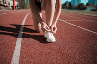 A woman tying her running shoes on a track