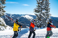 Three people carrying skis