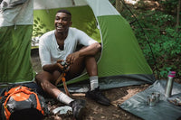 man relaxing in a tent in the forest