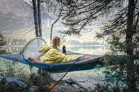 A woman sitting in a hammock with a sleeping bag