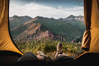 A person lying in a tent overlooking a mountain