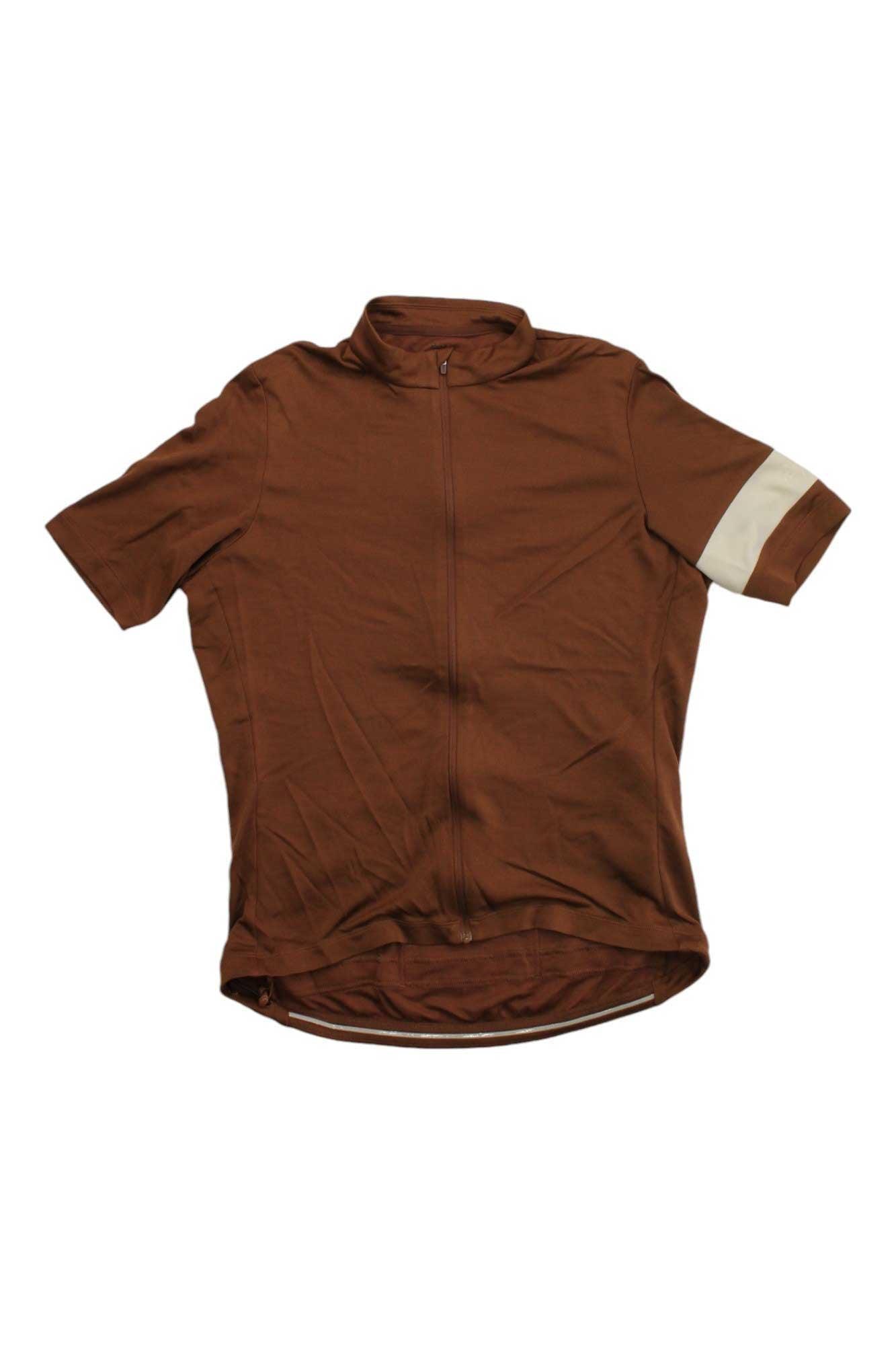The Rapha Mens Classic Jersey is a brown, short-sleeve merino wool cycling top with a front zipper and a beige stripe on the left sleeve, shown flat on a white background—premium apparel inspired by classic cycling style.