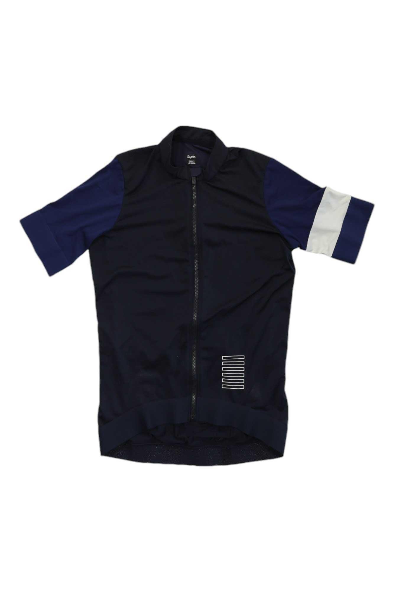 The Rapha Women's Pro Team Training Jersey is a short-sleeved, navy blue jersey featuring a front zipper, dark blue sleeves, a white stripe on the left sleeve, and a small white striped detail by the bottom right hem.