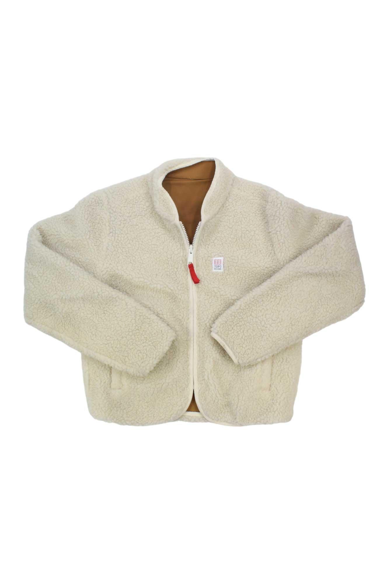 The Topo Designs Womens Sherpa Jacket is a cream-colored, long-sleeve fleece with a white zipper, brown inner lining, and a small white chest patch. Perfect for outdoor adventures, it's shown laid flat on a white background.