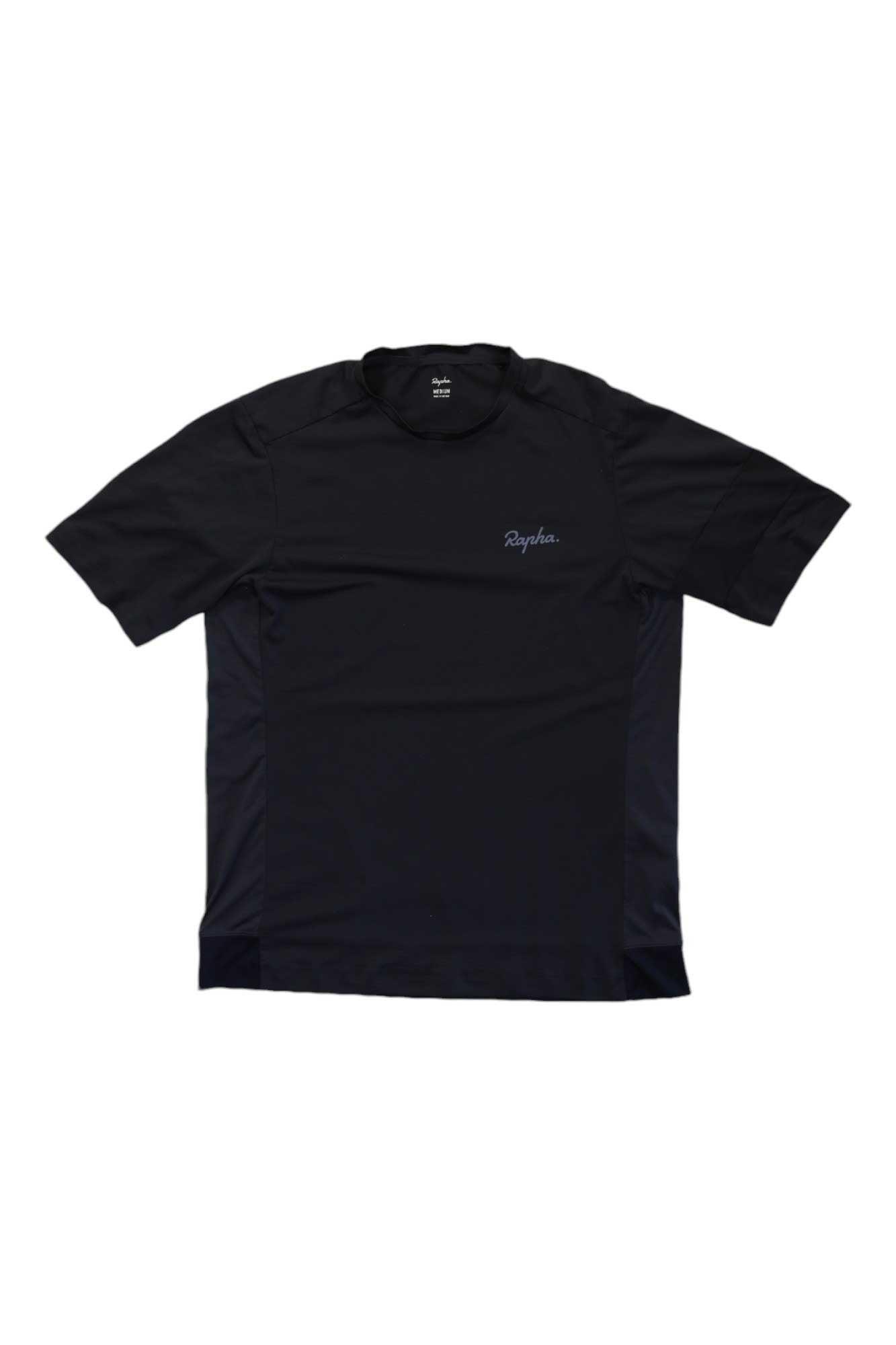 The Rapha Explore Technical T Shirt is a lightweight, breathable black cycling tee with short sleeves, subtle panel detailing, a crew neckline, and "Rapha" printed on the left chest.