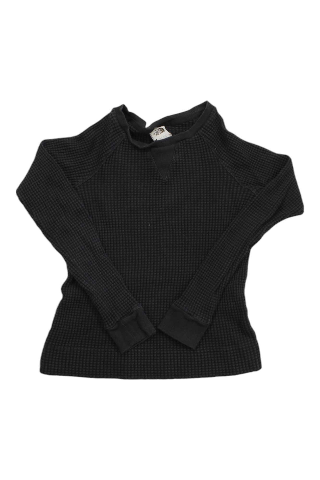 The North Face Womens Chabot LS Crew Top, a black long-sleeve cotton thermal knit shirt with ribbed cuffs and a crew neckline, is shown laid flat on a white background.
