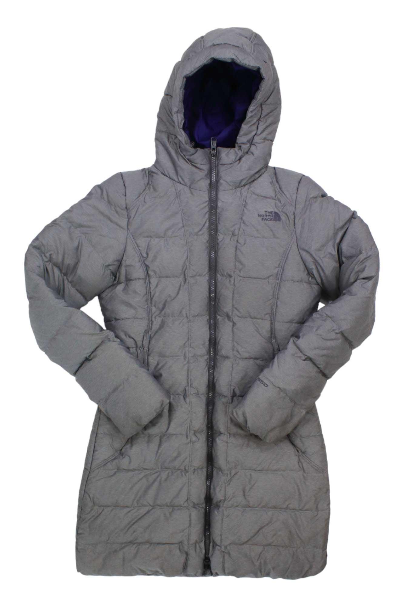 The North Face Womens Gotham Parka is a long, gray, quilted coat with a hood, front zipper, and chest logo. Made from recycled down, it features two side pockets and a water-repellent finish. Shown flat on a white background.