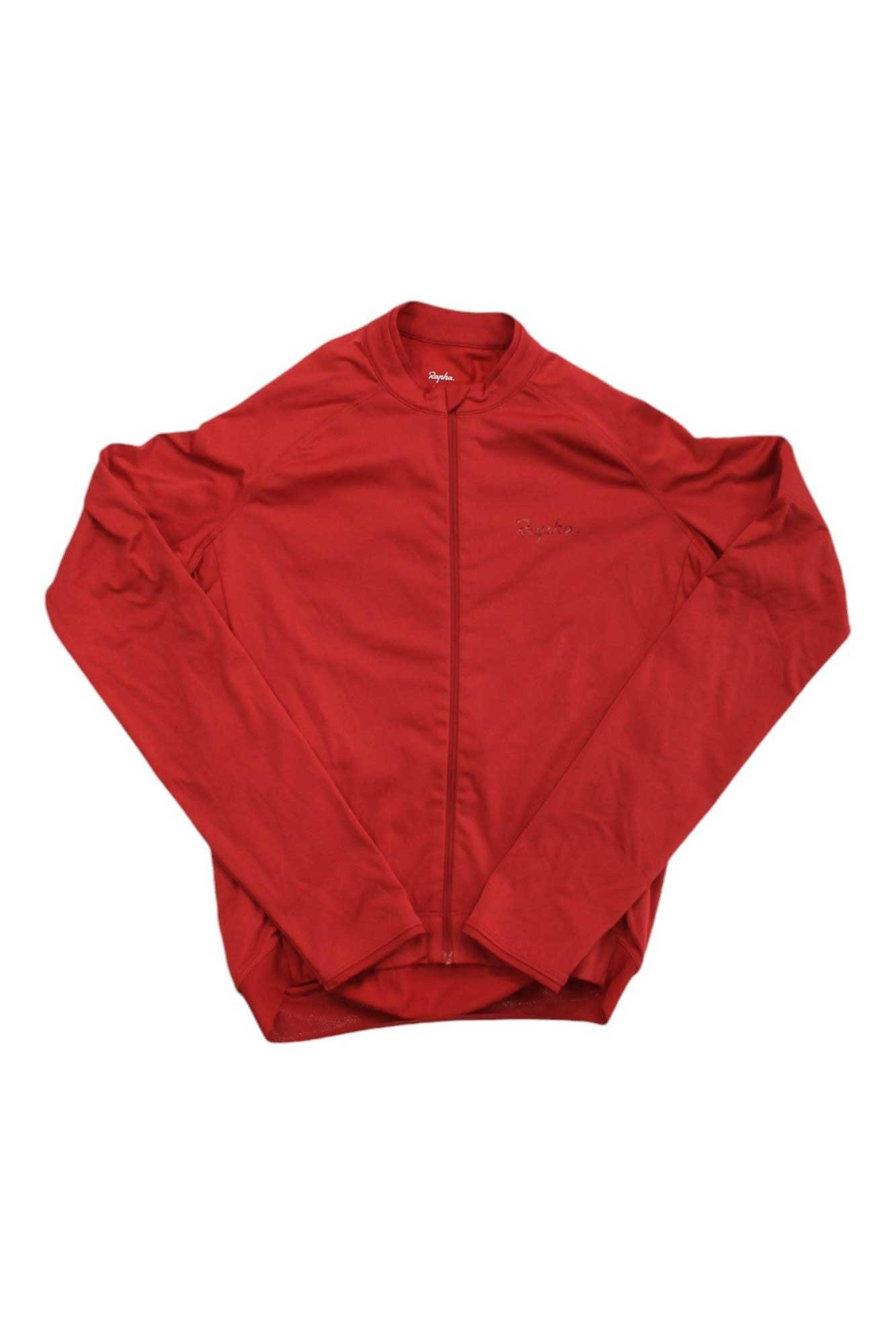 A red Rapha Mens Long Sleeve Core Jersey with a full front zipper is laid flat on a white background. This moisture-wicking cycling jersey features a subtle chest logo and a streamlined, simple design.