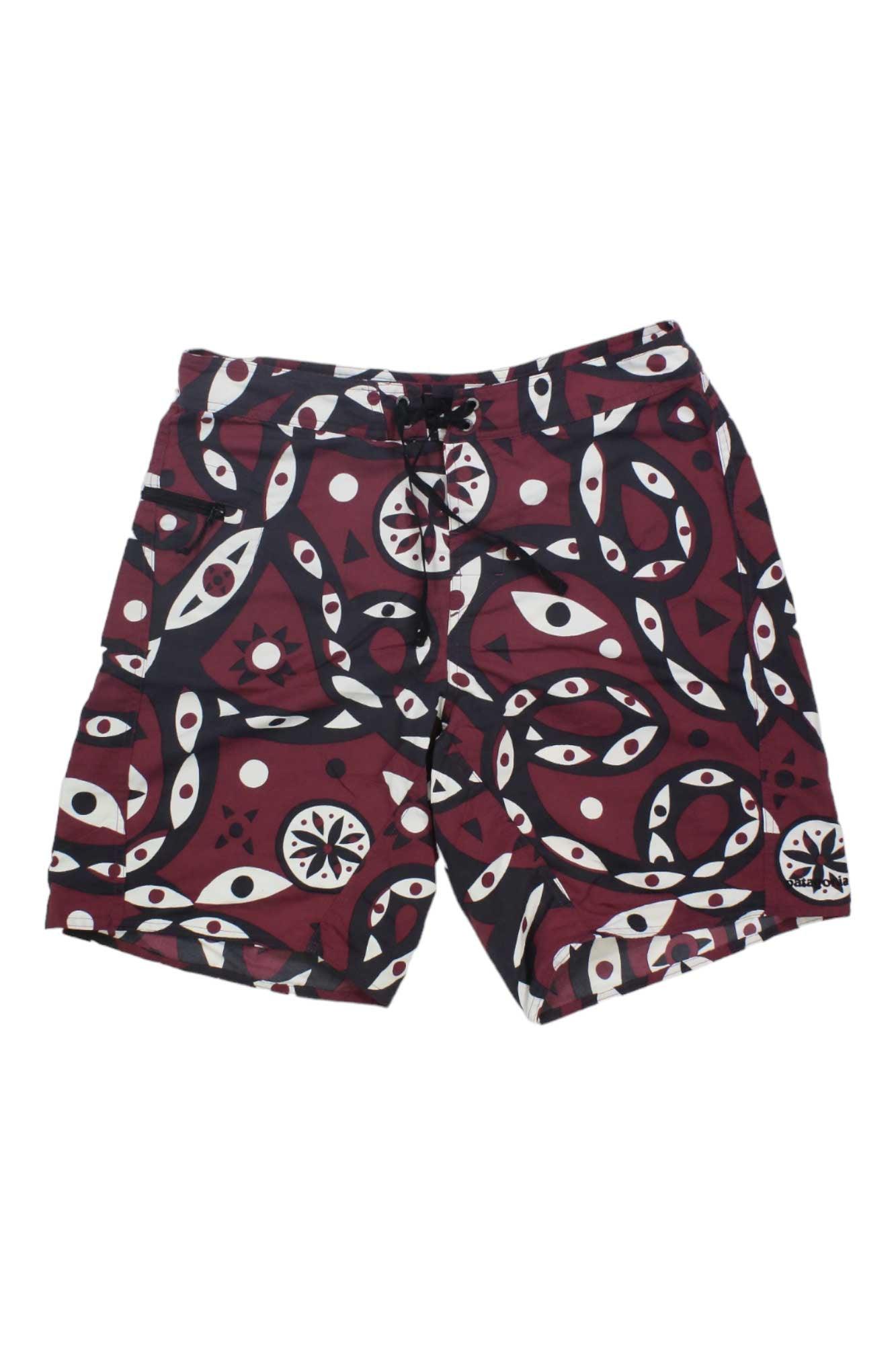 The Mens Wavefarer Boardshorts are maroon recycled nylon board shorts with a bold abstract pattern of white and black eyes, circles, and curves. Featuring a black waist drawstring and side pockets.
