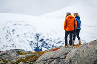 two women standing on a rock formation overlooking mountains