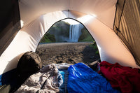 sleeping bags in a tent with a view of a waterfall