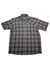 The Astroman Short Sleeve Shirt is a lightweight, button-up sun shirt with gray and black plaid, a collar, and left chest pocket. Designed for outdoor activities, it’s shown laid flat on a white background.