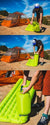 Wearing outdoor clothing, a person uses the Big Agnes Pumphouse Ultra to inflate a green camping air mattress beside an orange tent on rocky terrain under a blue sky.